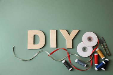 Ahşap harflerden yapılmış kısaltma DIY ve zeytin arka planda dikiş malzemeleri, düz yatıyordu