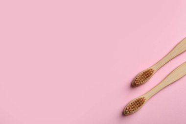 Pembe arka planda iki bambu diş fırçası, düz. Metin için boşluk