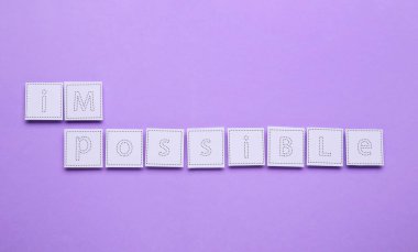 Motivasyon konsepti. Kelimeyi menekşe arkaplan üzerinde I ve M harfleri olan kağıdı kaldırarak İmkansıza çevirmek, üst görünüm