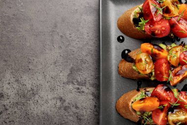 Avokado, domates ve balzamik sirke ile nefis bruschetalar. Gri desenli masa, üst manzara. Metin için boşluk