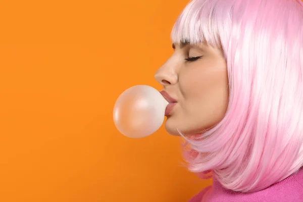 Beautiful woman blowing bubble gum on orange background, space for text