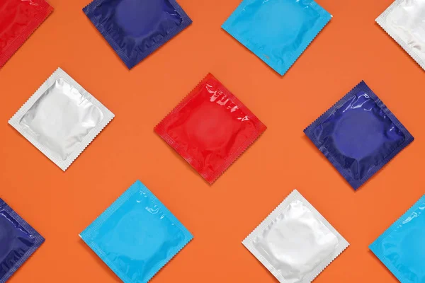 Packaged condoms on orange background, flat lay. Safe sex