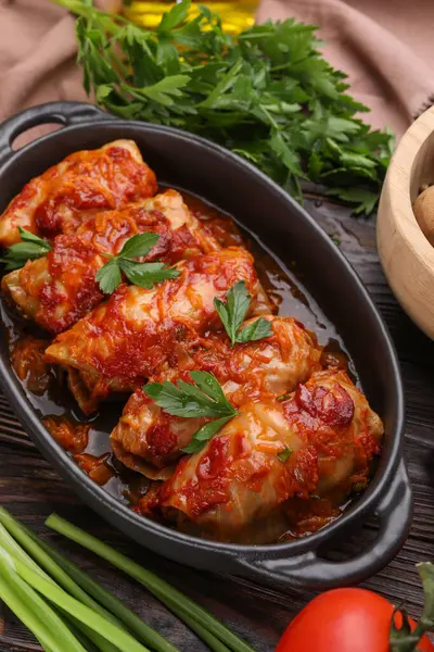 Delicious stuffed cabbage rolls cooked with tomato sauce on wooden table