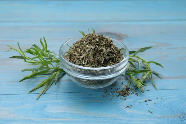 Dry and fresh tarragon on light blue wooden table