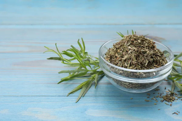 Dry and fresh tarragon on light blue wooden table, space for text