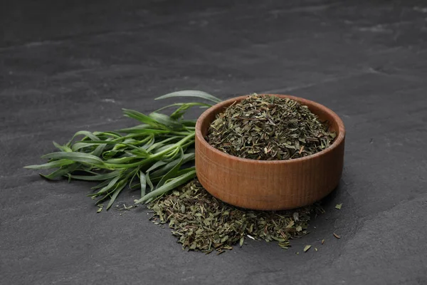 Dry and fresh tarragon on black textured table
