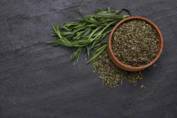 Dry and fresh tarragon on black textured table, flat lay. Space for text