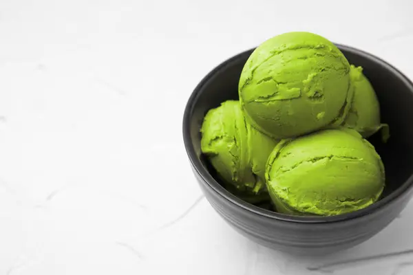 Tasty matcha ice cream in bowl on white textured table, space for text