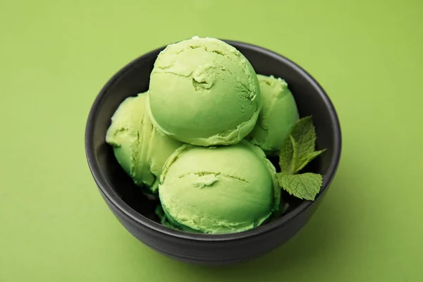 Tasty matcha ice cream in bowl on green table