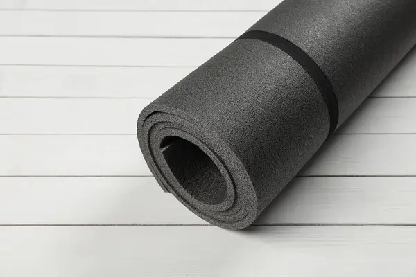 Yoga mat on white wooden floor. Space for text