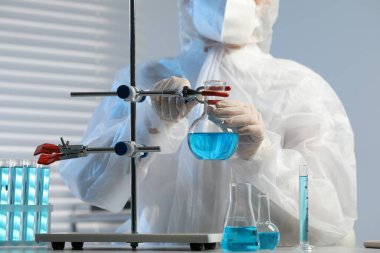 Laboratuvarda açık mavi sıvı matarasıyla çalışan bir bilim adamı.