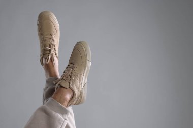 Açık gri arka planda şık ayakkabılar giyen bir adam, yakın plan. Metin için boşluk