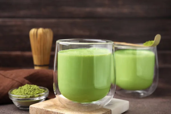 Glass of tasty matcha smoothie on brown table, closeup