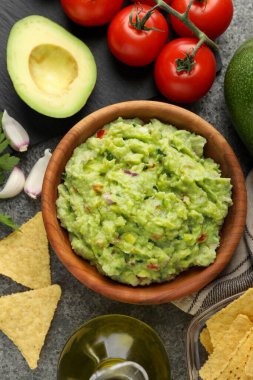 Gri masada nachos cipsi ve malzemelerle nefis guacamole.