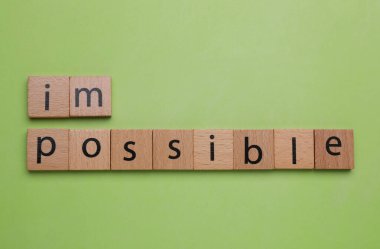 Motivasyon konsepti. Kelimeyi imkansızdan, açık yeşil arkaplandaki tahta kareleri kaldırarak olanaksıza çevirmek, düz yatıyordu