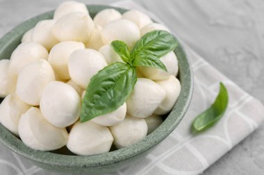 Lezzetli mozzarella topları ve fesleğen yaprakları gri masada, yakın plan. Metin için boşluk