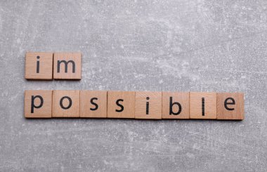 Motivasyon konsepti. Kelimeyi imkansızdan, açık gri tablodaki kareleri kaldırarak olanaksıza çevirmek, düz konum
