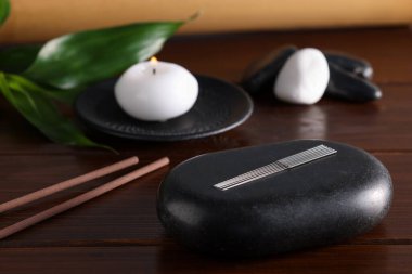 Akupunktur iğneleri ve masadaki spa taşı.
