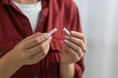 Sigara içmeyi bırak. Kırık sigara parçalarını arka planda tutan kadın, yakın plan.