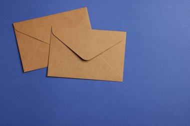 Mavi arka planda parşömen kağıdından yapılmış zarflar, düz. Metin için boşluk