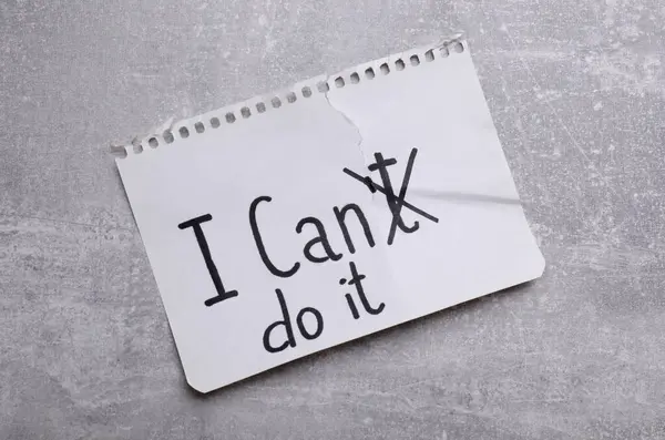 Motivation concept. Changing phrase from I Can\'t Do It into I Can Do It by crossing out letter T on light grey table, top view