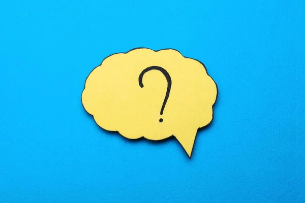 Paper speech bubble with question mark on light blue background, top view