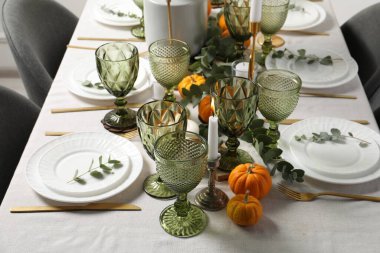 Güzel bir sonbahar sofrası. Tabaklar, çatal bıçak, gözlük, balkabağı ve çiçek dekoru.