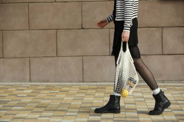 Bilinçli tüketim. Çevre dostu ürünlerle dolu bir çantayla dolaşan bir kadın, yakın plan. Metin için boşluk