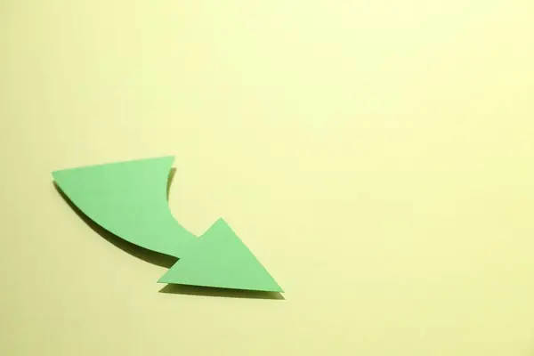 Curved green paper arrow on yellow background. Space for text
