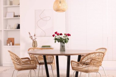 Yemek odasında vazo dolusu kırmızı gül çiçeği olan sandalyeler ve masa. Şık iç mekan