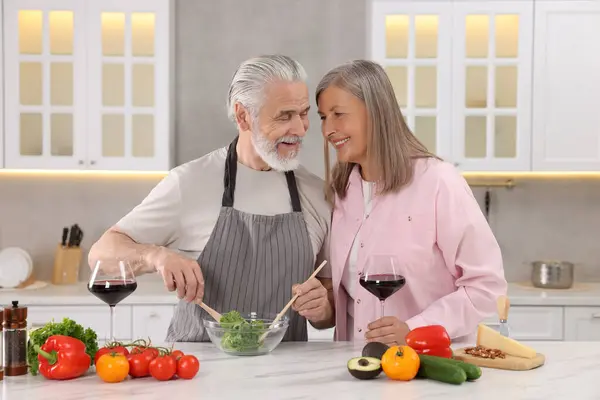 Affectionate senior couple cooking together in kitchen