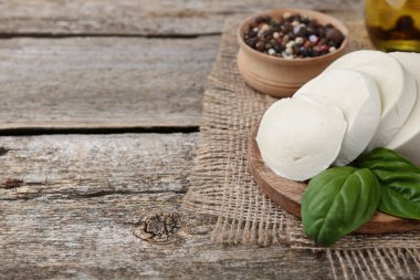 Ahşap masada lezzetli mozzarella dilimleri ve fesleğen yaprakları olan bir masa. Metin için boşluk