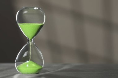 Açık gri arkaplan üzerinde yeşil kum akan kum saati, metin için boşluk