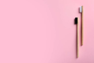 Pembe arka planda iki bambu diş fırçası, düz. Metin için boşluk