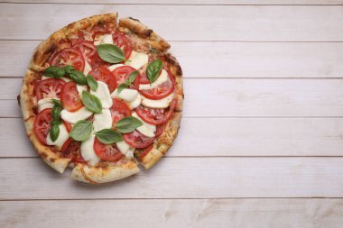 Domatesli lezzetli Caprese pizzası, mozzarella ve açık ahşap sehpada fesleğen. Metin için boşluk