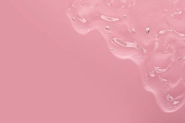 Açık pembe arka planda şeffaf temizleme jeli, metin için yeri olan üst görünüm. Kozmetik ürünü