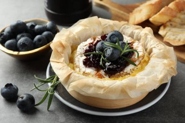 Yaban mersinli, reçelli ve biberiyeli lezzetli brie peyniri. Gri masada, yakın plan.