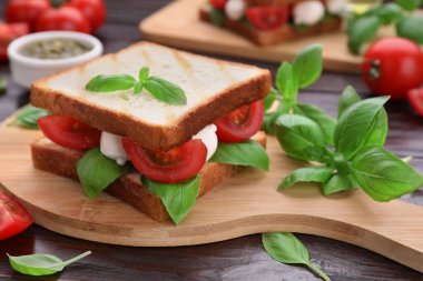 Nefis Caprese sandviçi, mozzarella, domates, fesleğen ve pesto sosu ahşap masada, yakın plan.