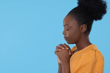 Elleri sımsıkı bağlı bir kadın açık mavi arka planda Tanrı 'ya dua ediyor. Metin için boşluk