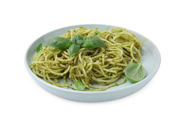 Pesto soslu bir tabak lezzetli makarna ve beyaz üzerine izole edilmiş fesleğen