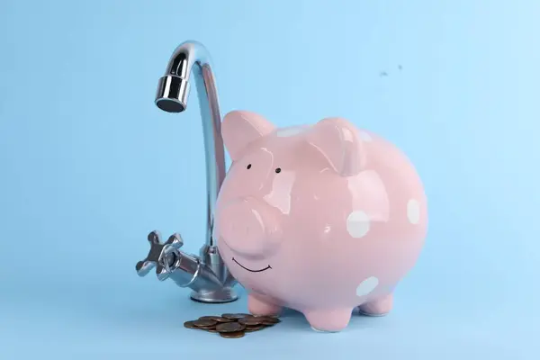 Water scarcity concept. Piggy bank, tap and coins on light blue background