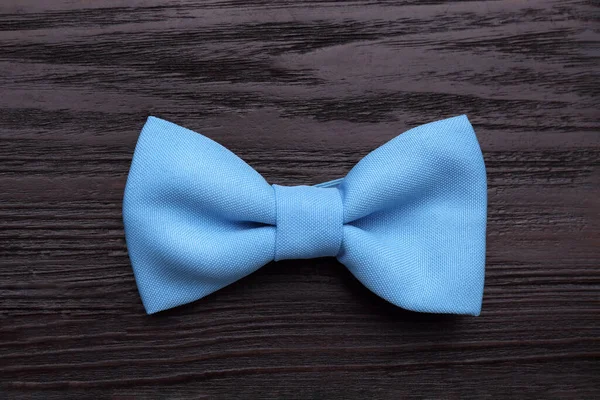 Stylish light blue bow tie on wooden table, top view