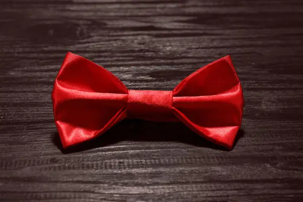 Stylish red bow tie on wooden table, closeup
