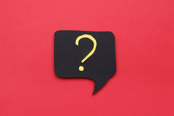Paper speech bubble with question mark on red background, top view