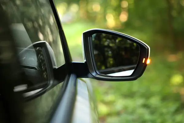 Side view mirror of modern car on blurred background, closeup