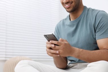 Modern cep telefonunu kapalı mekanda kullanan adam, yakın plan. Metin için boşluk