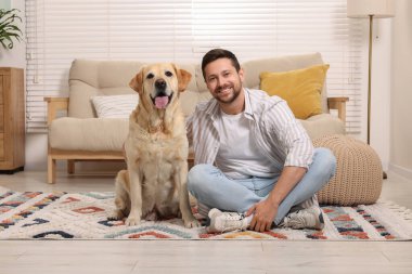 Adam evde sevimli Labrador Retriever köpeğine sarılıyor. Sevimli hayvan