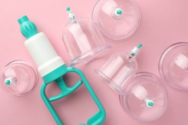 Pembe arka planda plastik bardaklar ve el pompamız var. Fincan terapisi.