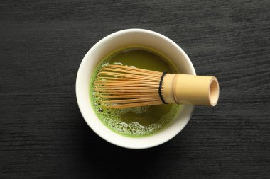 Siyah ahşap masada bambu çırpıcılı taze kibrit çayı.