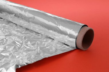 Turuncu arka planda alüminyum folyo rulosu, yakın plan.